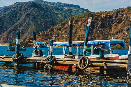 boat beside dock on body of water during daytime thumbnail