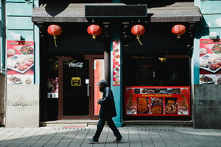 man walking on street beside food store during daytime thumbnail