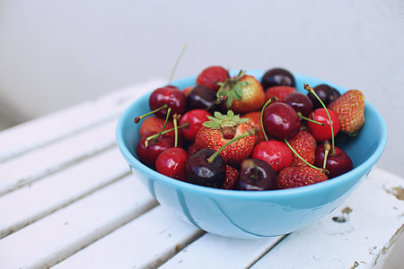 red strawberries and cherries in blue ceramic bowl thumbnail