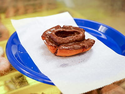 A cake donut with chocolate icing sitting on a blue plate. thumbnail