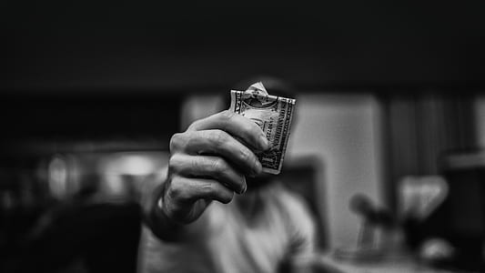 person holding 1 US dollar banknote in grayscale photography thumbnail