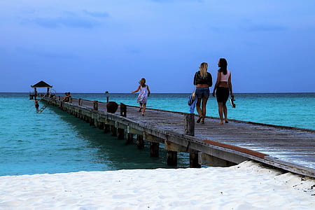 women and child walking on sea dock under blue skies thumbnail