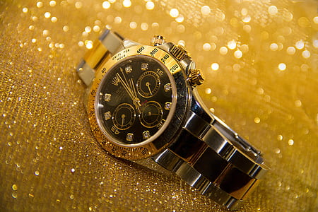 round gold-colored and black Rolex analog watch with link band thumbnail