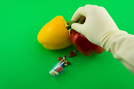 right person's hand holding two red and yellow bell peppers thumbnail
