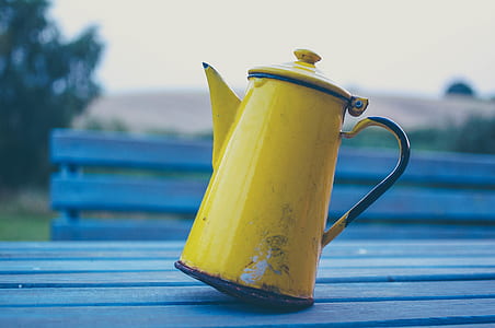 focus photo of yellow metal teapot on blue wooden board thumbnail