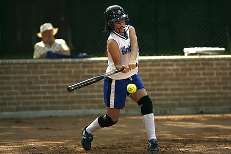 Woman in White Sleeveless Jersey Holding a Black Baseball Bat Pitching the Green Tennis Ball thumbnail