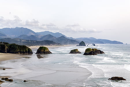 rocks on shore with mountains at distance thumbnail