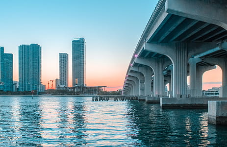 Body of Water Under Bridge Near Buildings thumbnail