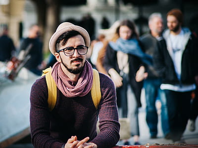 Man Sitting Next to Couple of Person Walking on the Street during Daytime thumbnail