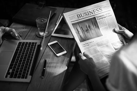 grayscale photo of man holding business paper beside table thumbnail