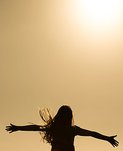 silhouette of woman spreading her hands photo thumbnail