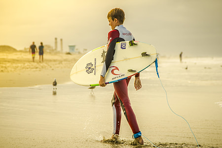 person holding skimboard standing on sand thumbnail