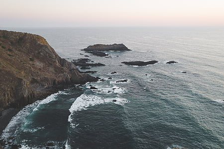aerial photography of body of water and rock mountain during daytime thumbnail