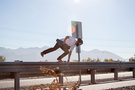 person holding skateboard jumping on road rail during daytime thumbnail