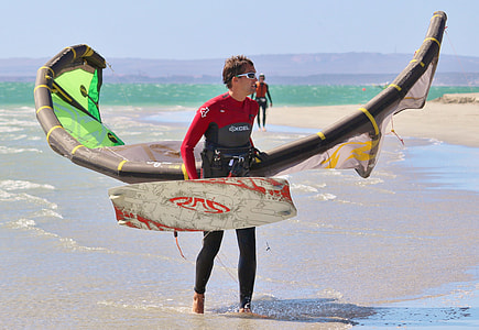 person holding wakeboard and wind glider on beach shore thumbnail