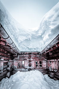 brown wooden cabin covered with thick snow thumbnail
