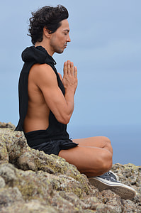 man in black shirt meditating on brown stone surface during daytime thumbnail