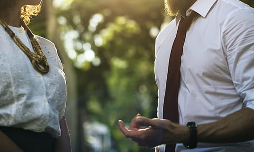 man and woman talking near trees thumbnail