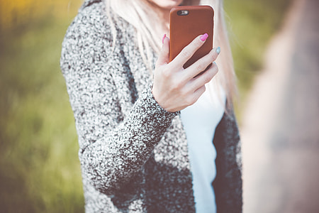Young Woman Holding Her iPhone in Leather Case thumbnail