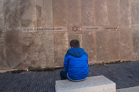boy in blue jacket sitting in front of monument thumbnail