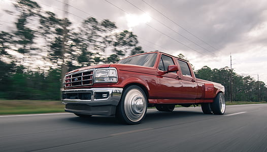 red Ford F-series crew cab pickup truck on road near trees thumbnail