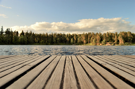 brown wooden dock beside body of water under blue sky thumbnail