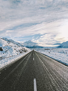 snowy mountain near road under cloudy sky during daytime thumbnail