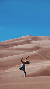 woman dancing in the middle of the dessert during daytime thumbnail