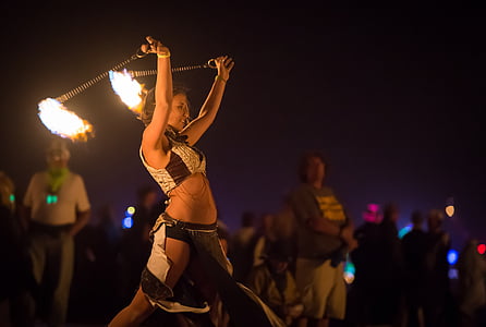 woman wearing white and black dress fire dancing surrounded with crowd thumbnail