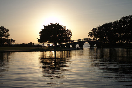 silhouette photo of bridge above rippling body of water during golden hour thumbnail