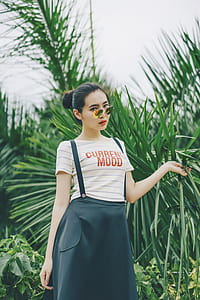 woman in white striped current mood-printed shirt standing near plants thumbnail