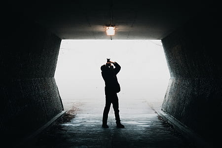man standing in the middle of a tunnel during daytime thumbnail