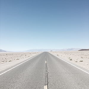 gray concrete road between desert thumbnail