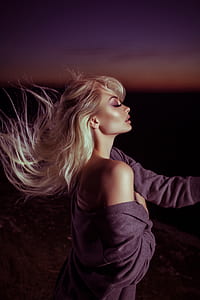 woman wearing cardigan taking photo during night thumbnail
