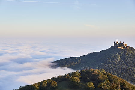 brown building on cliff overlooking clouds at daytime thumbnail