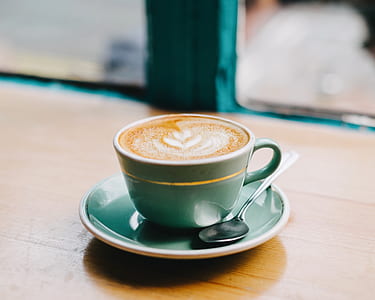 teal ceramic tea cup with coffee inside on brown wooden surface thumbnail