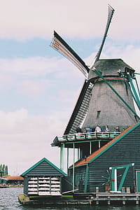 People Walking on Windmill Near Body of Water thumbnail