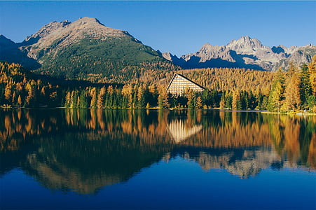 house near body of water and mountain range thumbnail
