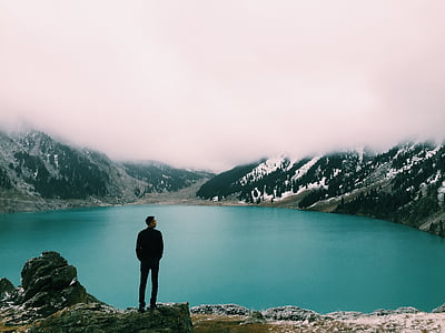 man on top of mountain beaside body of water thumbnail