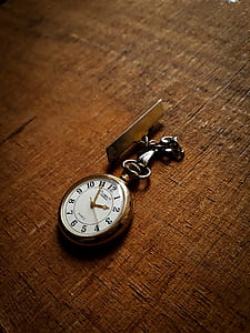 round gold-colored pocket watch on brown surface thumbnail