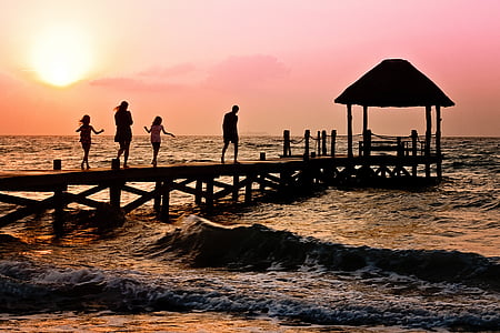 photography of silhoutte of four persons walking on sea dock thumbnail
