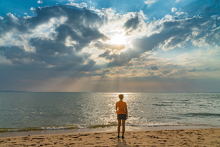 photo of person standing seashore facing ocean during day time thumbnail
