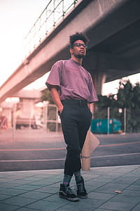 man standing under gray bridge under clear sky thumbnail