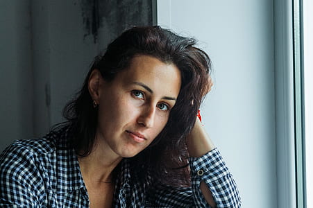 Woman in Black and White Gingham Long-sleeved Top Holding Her Hair Beside White Surface thumbnail