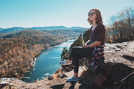 woman sitting on rocks near body of water thumbnail