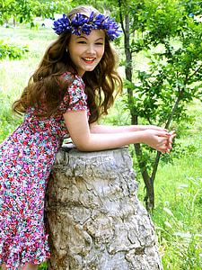 woman wearing floral dress and purple headdress smiling looking on camera thumbnail