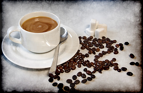 white ceramic teacup with coffee in it beside coffee beans thumbnail