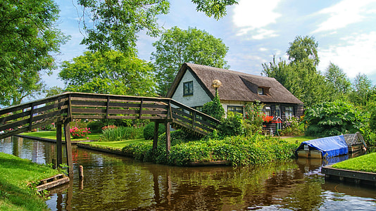 landscape photography of brown house near brown bridge across body of water at daytime thumbnail