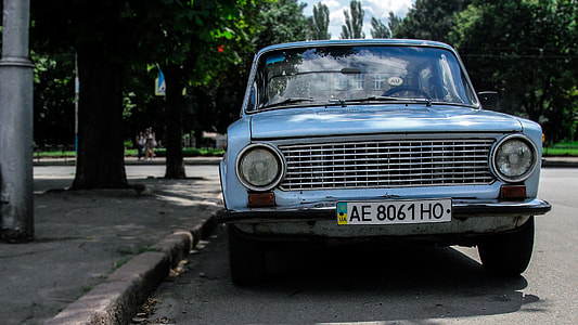 blue car parked near grey street light post under the shade of a tree during daytime thumbnail