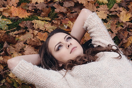 woman laying on dried leaves photo thumbnail